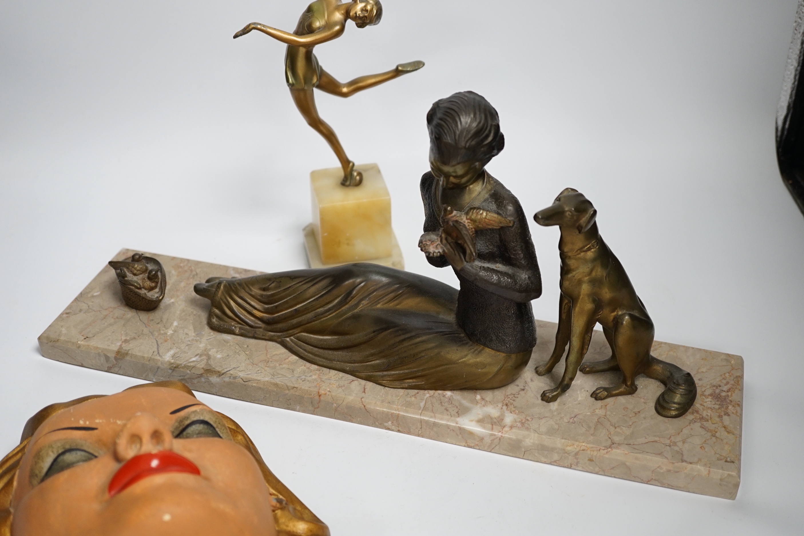 An Art Deco model of a seated lady with a dog and doves, together with a figure of dancing girl and painted plaster face mask, longest 45cm